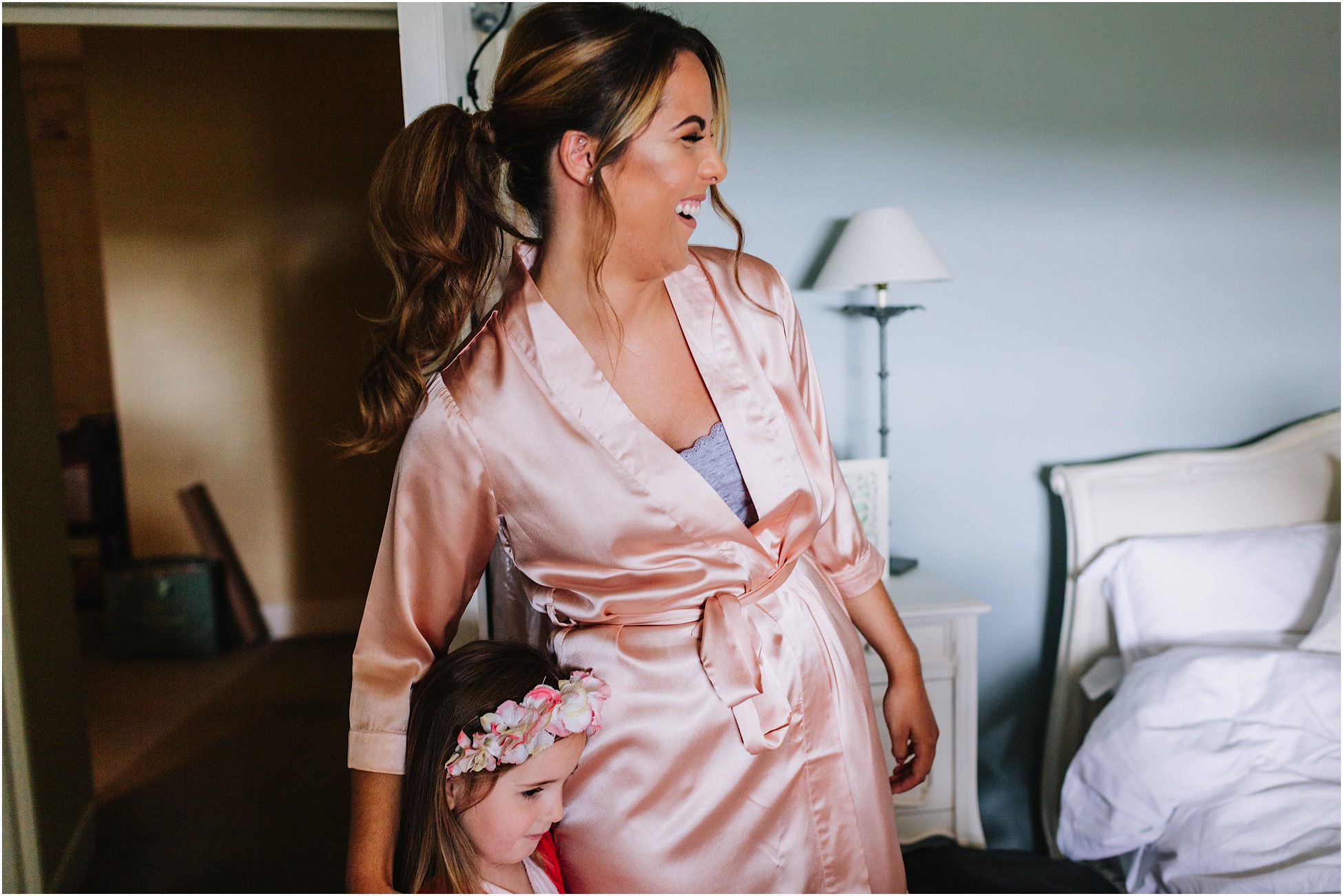 Bridesmaid and flower girl laugh during bridal prep