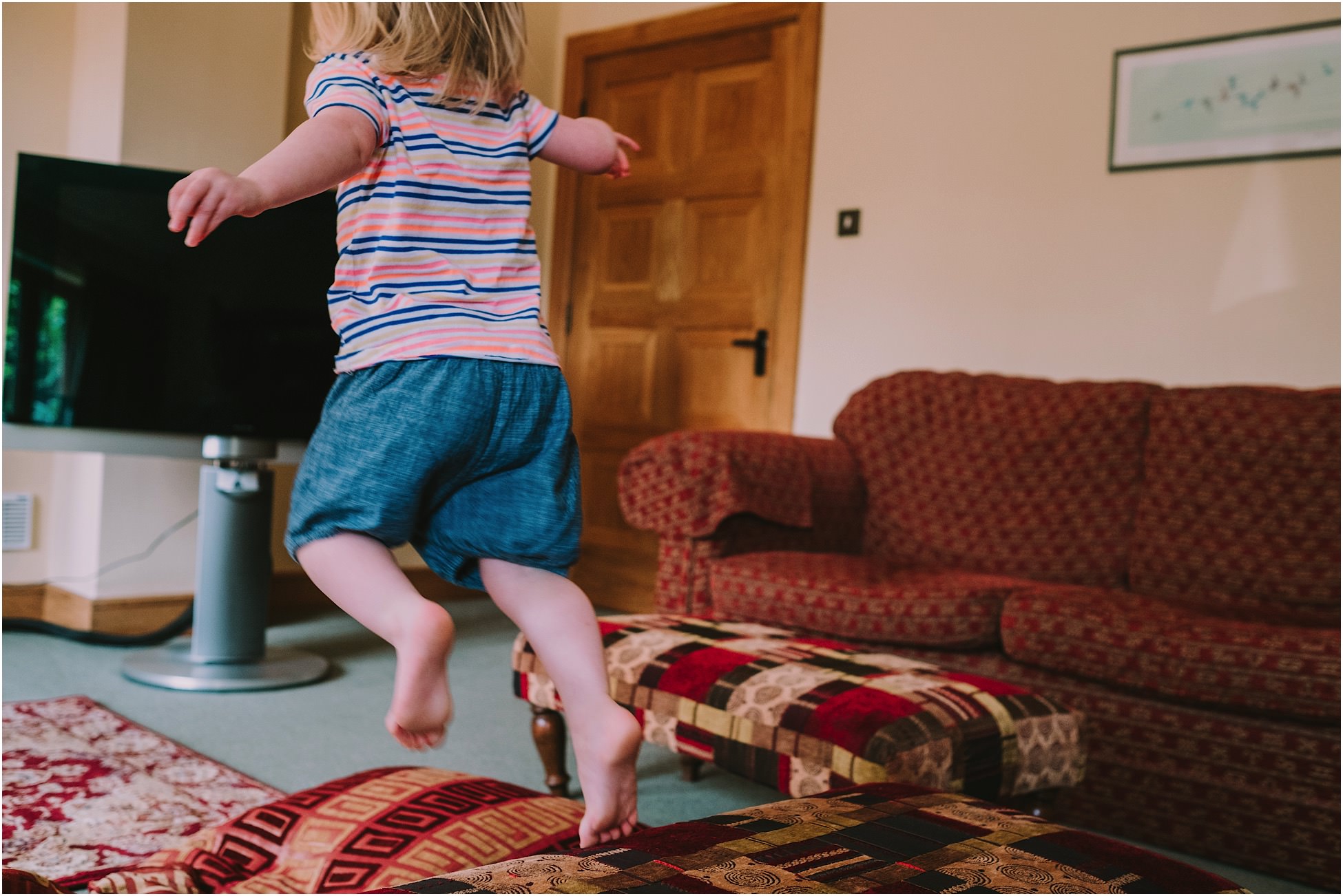 Little flower girl jumping off a sofa
