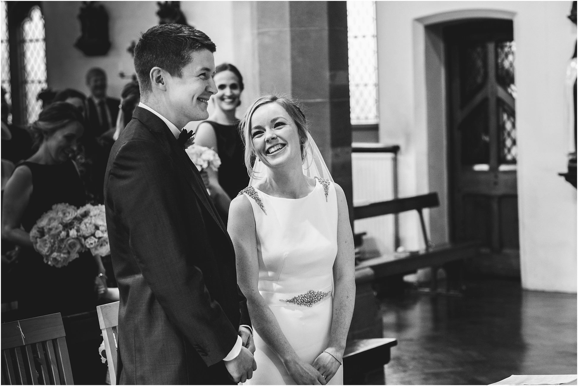 Black and white image of bride and groom stood in church